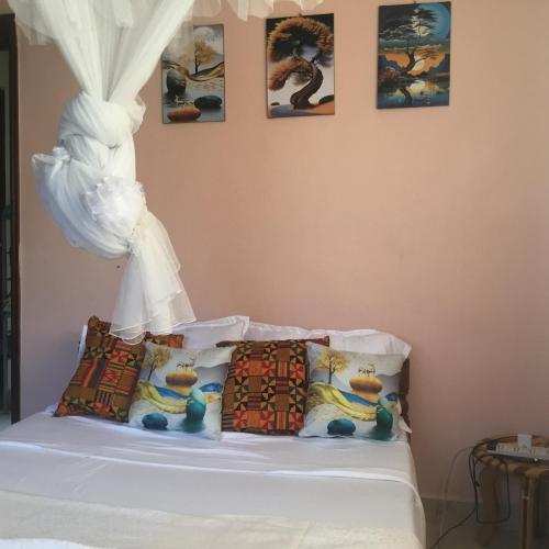 a bedroom with a bed with four pictures on the wall at Nam Garden in Kisumu