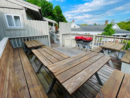 a wooden deck with two benches and a table at Waters Edge Lodge in Lake George
