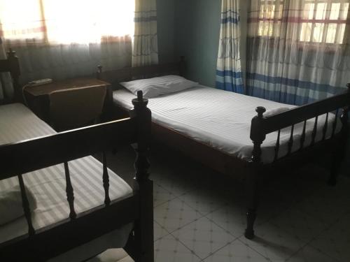 two twin beds in a room with a window at Nam Garden in Kisumu