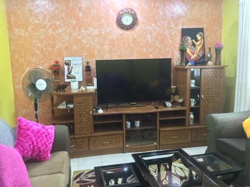 a living room with a television on a wooden entertainment center at Nam Garden in Kisumu