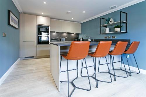 a kitchen with orange chairs at a counter at Troon No 1 Apartments in Troon