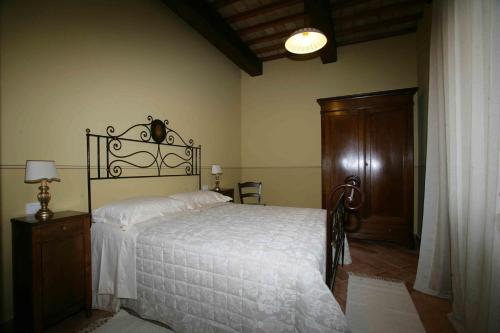 a bedroom with a white bed and a wooden cabinet at Casa Vacanze Residenza Bocci in Foligno