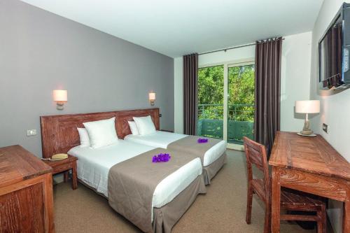 a bedroom with a bed with purple flowers on it at Hôtel Campo Dell'oro in Ajaccio