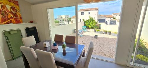 une salle à manger avec une table et une grande fenêtre dans l'établissement Maison 4 chambres lumineuse Proche mer, à Sérignan