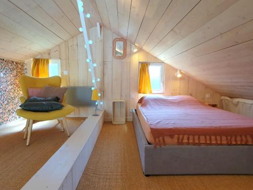 - une chambre avec un grand lit et une chaise jaune dans l'établissement Les Bonnes Ondes - Chalet breton bord de mer - Baie Mont St Michel, à Saint-Benoît-des-Ondes