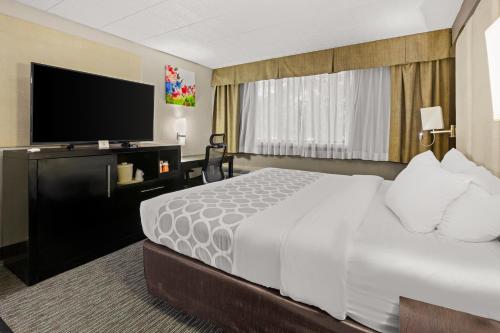 a hotel room with a bed and a flat screen tv at Suburban Studios in Altoona