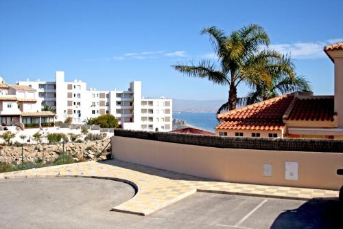 a view of a building with a palm tree and the ocean at Bungalow con piscina 28 in Gran Alacant