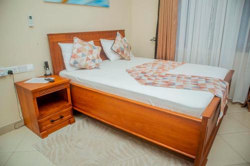 a bedroom with a wooden bed with a night stand at Plavender Inn in Dar es Salaam