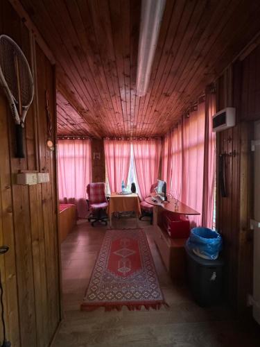 a living room with a table and pink curtains at Vila Lacul Caldarusani in Grădiştea