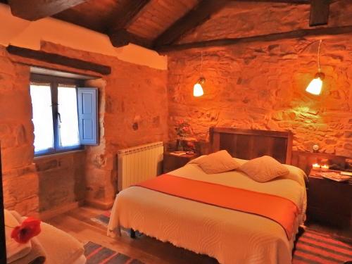 1 dormitorio con 1 cama en una pared de piedra en La Casa De Murias, en Murias de Rechivaldo