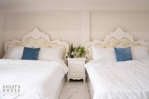 two beds with white sheets and blue pillows in a bedroom at Hailey's House in Da Lat