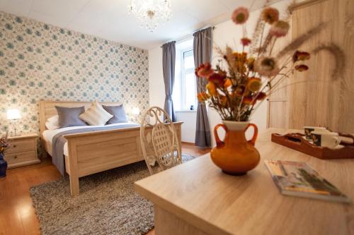 1 dormitorio con 1 cama y un jarrón de flores sobre una mesa en Apartments Artorius Laško en Laško