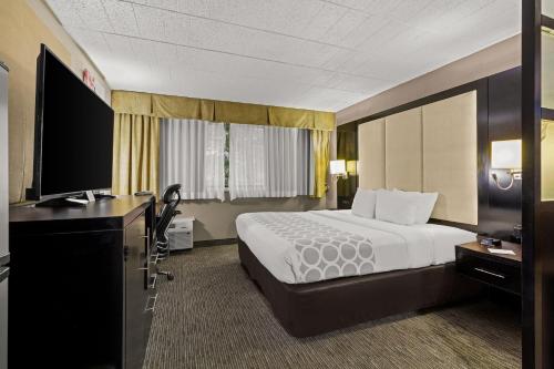 a hotel room with a bed and a flat screen tv at Suburban Studios in Altoona
