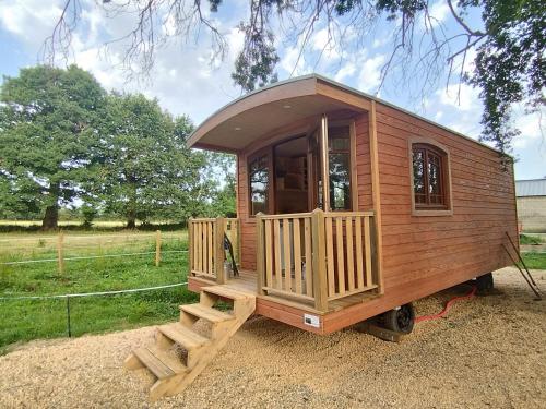 a wooden tiny house with a porch and stairs at Roulotte tout confort à la ferme in Saint-Lumine-de-Coutais