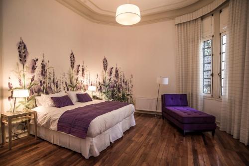 a bedroom with a large bed and a purple chair at Matildas Hotel Boutique in Santiago