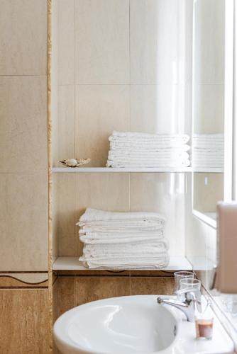 a bathroom with a sink and towels on a shelf at Titi's Villa in Durrës