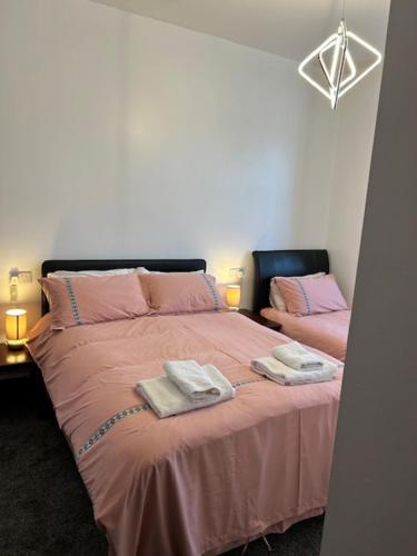 a bedroom with two beds with pink sheets and towels at Holland House in Great Yarmouth