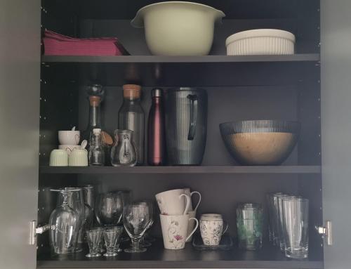 a shelf filled with various glass bottles and cups at Mysig 1a med Minispa, 20 min från Kinnekulle in Götene