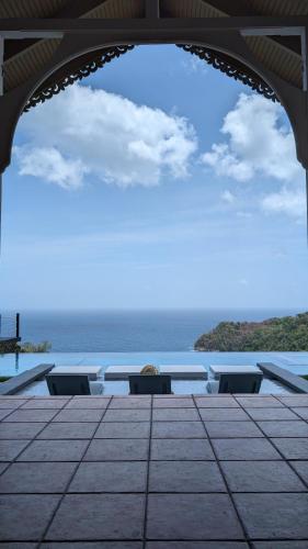 a view of the ocean from a patio with a table and chairs at Silk Cotton Cottages in Parrot Hall