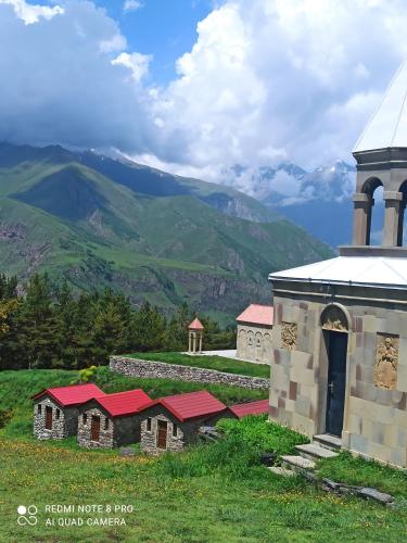 a church and a hill with mountains in the background at Crystal Kazbegi in Stepantsminda