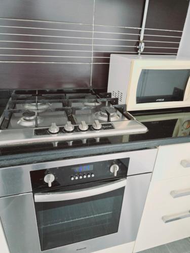a stove top oven in a kitchen next to a microwave at Karray Home Appartement Salon 2 RDC avec Jardin in Hammamet