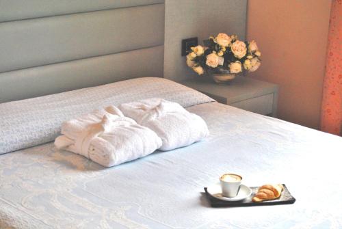 a bed with two towels and a tray with a cup of coffee at Hotel La Meridiana in Urbino