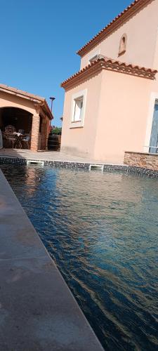 une maison avec une piscine d'eau en face de celle-ci dans l'établissement Chez Delphine, à Théza