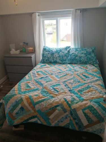 a bed with a quilt on it in a bedroom at Harbour House Twillingate in Twillingate