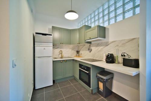 une cuisine avec des armoires vertes et un réfrigérateur blanc dans l'établissement oliveraie, à Nice