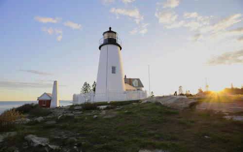 a lighthouse sitting on top of a hill next to the ocean at Hotel Pemaquid in Bristol