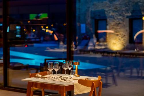 a table with wine glasses on it with a pool at Cherry Sculpture Hotel in Paul