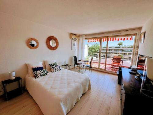 a bedroom with a large white bed and a balcony at piscine, parking, vue mer, 23 m2 in Saint-Tropez
