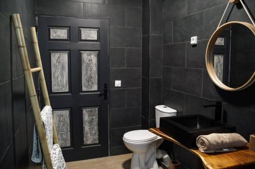 Baño negro con aseo y espejo en Villa Savio, en Saint-Pierre