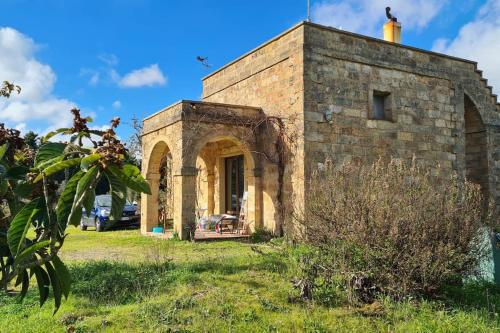 an old stone building in a grassy field at Taverna Ursula Salento in Tricase