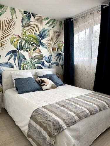 une chambre avec un lit avec un papier peint tropical dans l'établissement La Villa du Soleil, à Saint-Cyprien