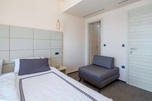 a bedroom with a bed and a chair at Villa Luna Mare mit Pool und Sauna in Podaca