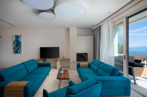 a living room with blue couches and a tv at Villa Luna Mare mit Pool und Sauna in Podaca