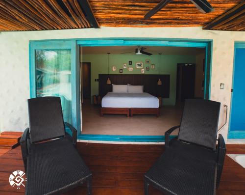 a bedroom with a bed and two chairs on a deck at Hacienda Susulá in Susulá
