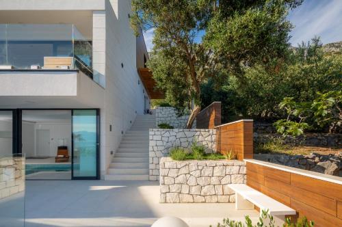 a modern house with a glass door and stairs at Villa Luna Mare mit Pool und Sauna in Podaca