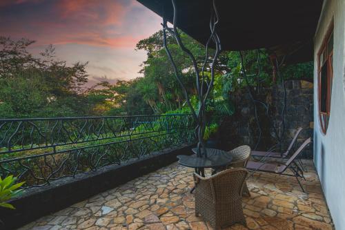 a patio with a table and chairs and an umbrella at Finca Rosa Blanca Coffee Farm and Inn in Heredia