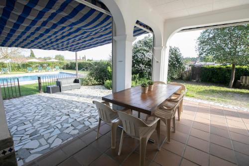 a patio with a wooden table and chairs and a pool at El Olmo in Posadas