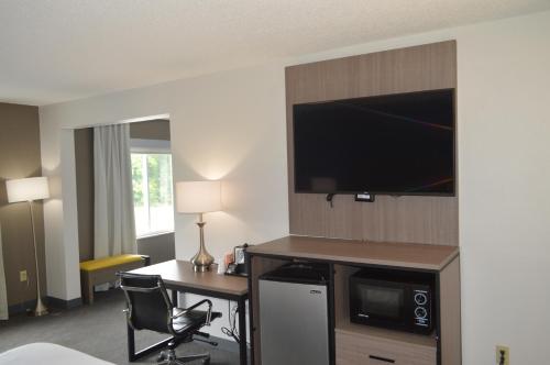 a hotel room with a desk and a flat screen tv at Comfort Inn & Suites Harrisburg-Hershey North in Harrisburg