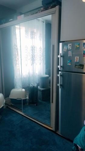 Cette chambre dispose d'une porte coulissante en verre et d'un réfrigérateur. dans l'établissement Appartement, à Aubervilliers