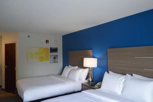 two beds in a hotel room with a blue wall at Comfort Inn & Suites Harrisburg-Hershey North in Harrisburg