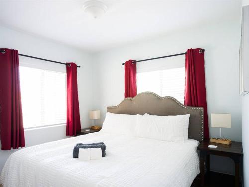 a bedroom with a white bed with red curtains at Family Renovated Home, Netflix, AC, WD, Putt Putt in Fullerton
