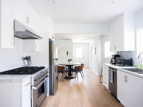 a kitchen with white cabinets and a table in it at Family Renovated Home, Netflix, AC, WD, Putt Putt in Fullerton