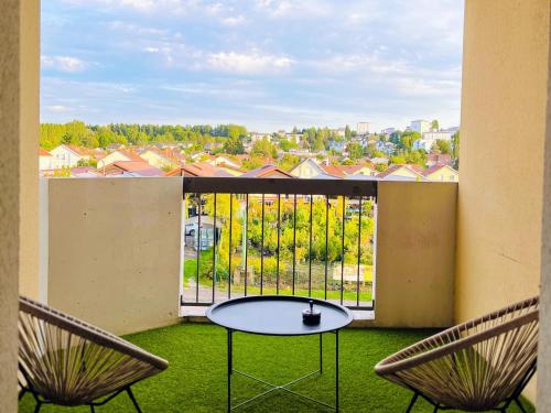 un balcon avec une table et deux chaises et une fenêtre dans l'établissement Appartement tout confort avec Baby-foot, à Épinal