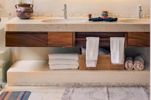une salle de bain avec un lavabo et une étagère avec des serviettes dans l'établissement Armadillo Living Villas, à Zihuatanejo
