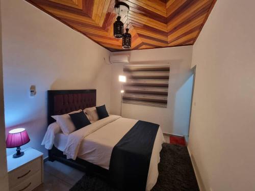a bedroom with a bed and a wooden ceiling at Baobab Lodge Douala - Makepe in Douala