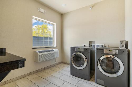 a laundry room with two washing machines and a window at Cobblestone Hotel & Suites - Alpine in Alpine